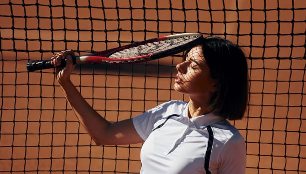 Having a break. Female tennis player is on the court at daytime.