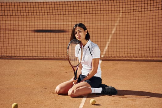 In black skirt. Female tennis player is on the court at daytime.