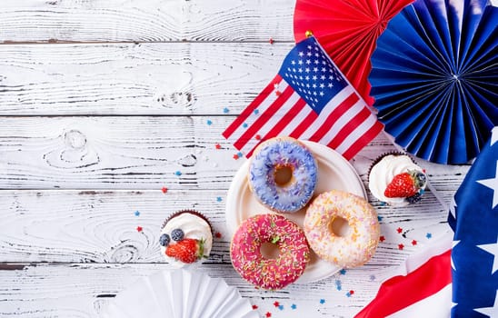 Fourth of july celebration. Sweet cupcakes and donuts with usa flag on wooden background