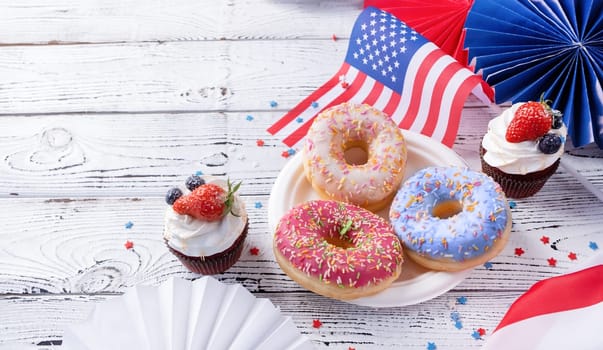 Fourth of july celebration. Sweet cupcakes and donuts with usa flag on wooden background