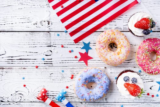 Fourth of july celebration. Sweet cupcakes and donuts with usa flag on wooden background