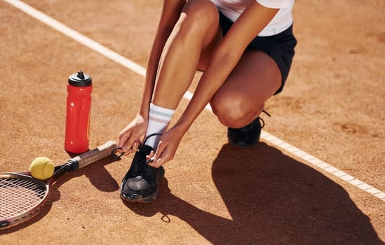 Wearing shoes. Female tennis player is on the court at daytime.