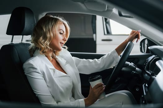 In the car. Woman in formal clothes is indoors in the autosalon.