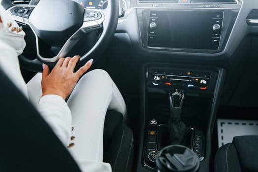 Vehicle interior. Woman in formal clothes is indoors in the autosalon.