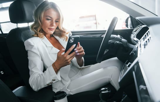 Vehicle interior. Woman in formal clothes is indoors in the autosalon.