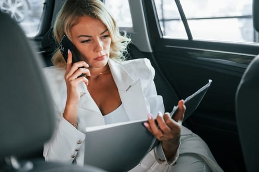 Vehicle interior. Woman in formal clothes is indoors in the autosalon.