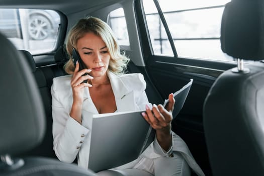 Working in the car. Woman in formal clothes is indoors in the autosalon.