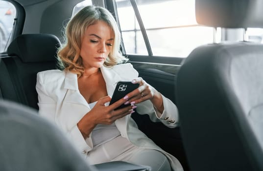 Working in the car. Woman in formal clothes is indoors in the autosalon.