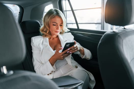 Working in the car. Woman in formal clothes is indoors in the autosalon.