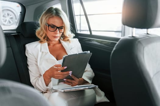Working in the car. Woman in formal clothes is indoors in the autosalon.