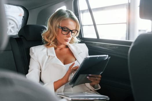 Working in the car. Woman in formal clothes is indoors in the autosalon.