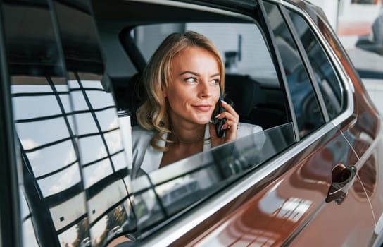 Side view. Woman in formal clothes is indoors in the autosalon.