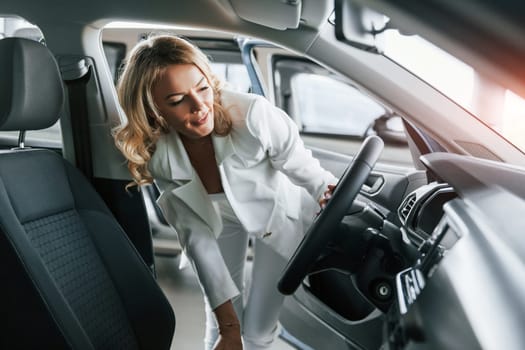 Through open door. Woman in formal clothes is indoors in the autosalon.