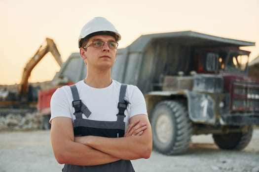 Near loading vehicle. Worker in professional uniform is on the borrow pit at daytime.