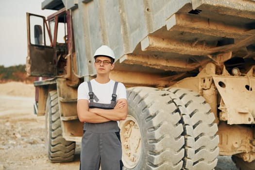 Near loading vehicle. Worker in professional uniform is on the borrow pit at daytime.