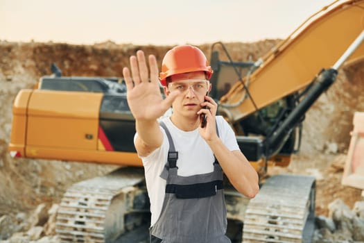 Portrait of worker in professional uniform that is on the borrow pit at daytime.