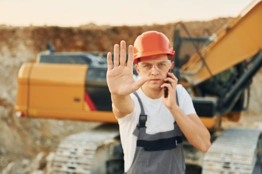 Portrait of worker in professional uniform that is on the borrow pit at daytime.