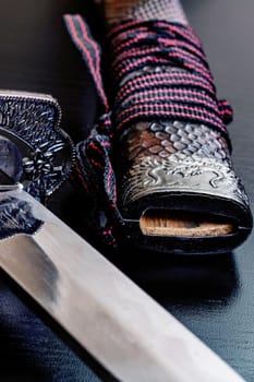 Samurai sword on a black wooden table close up