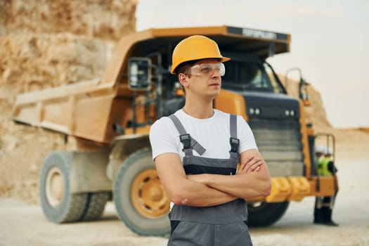 Professional loading vehicle. Worker in uniform is on the borrow pit at daytime.