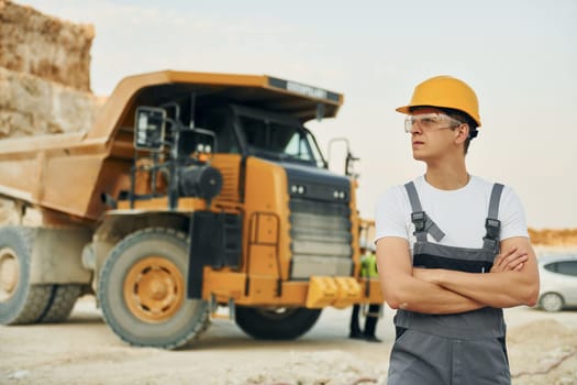 Professional loading vehicle. Worker in uniform is on the borrow pit at daytime.