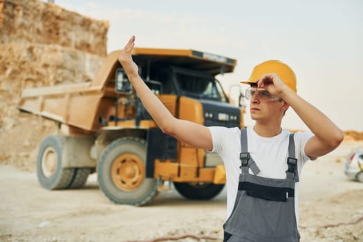 Professional loading vehicle. Worker in uniform is on the borrow pit at daytime.