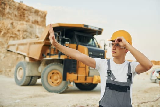 Professional loading vehicle. Worker in uniform is on the borrow pit at daytime.