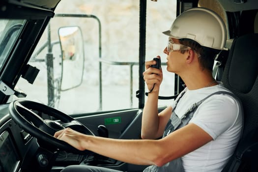 Driving transport. Worker in professional uniform is on the borrow pit at daytime.