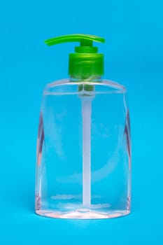 Green liquid soap dispenser on blue background close up
