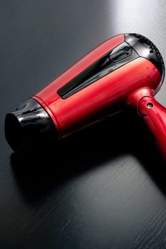 Red hairdryer on a black wooden table close up