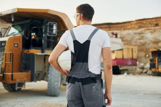 Rear view. Worker in professional uniform is on the borrow pit at daytime.