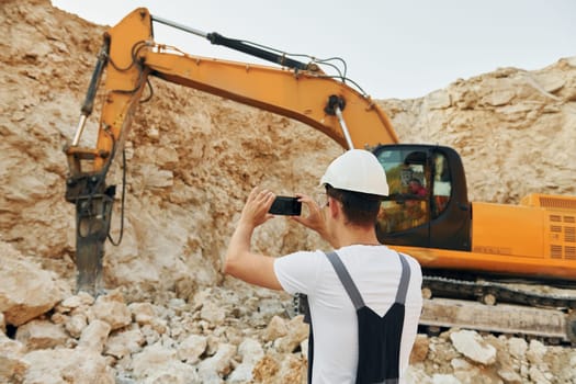 Big career. Worker in professional uniform is on the borrow pit at daytime.