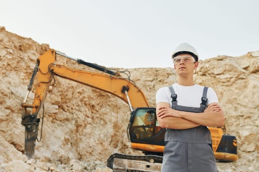 Big career. Worker in professional uniform is on the borrow pit at daytime.