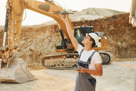Control of the project. Worker in professional uniform is on the borrow pit at daytime.
