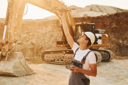 Control of the project. Worker in professional uniform is on the borrow pit at daytime.