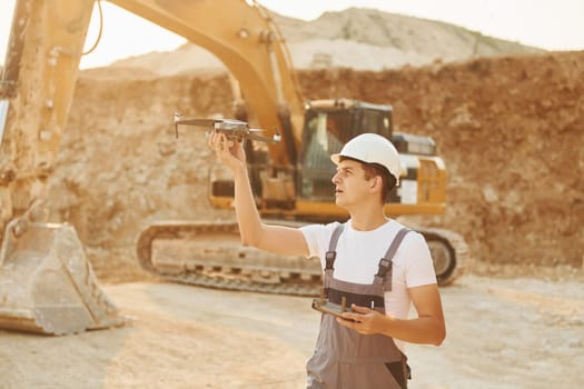 Control of the project. Worker in professional uniform is on the borrow pit at daytime.