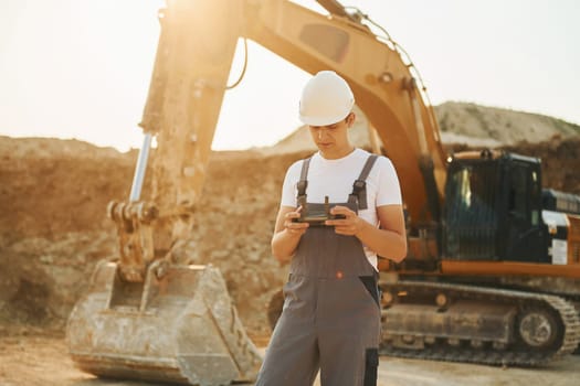 Illuminated by sunlight. Worker in professional uniform is on the borrow pit at daytime.