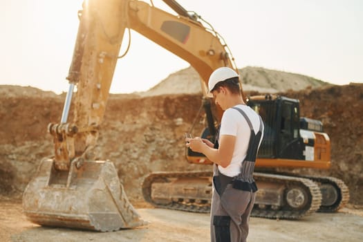 Illuminated by sunlight. Worker in professional uniform is on the borrow pit at daytime.