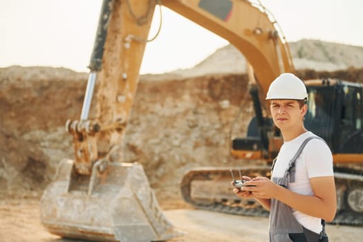Illuminated by sunlight. Worker in professional uniform is on the borrow pit at daytime.