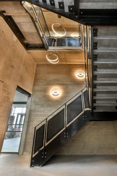 the inside of a building that looks like it's going down some stairs with lights hanging from above them