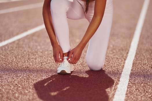 Conception of bodycare. Young woman in sportive clothes is exercising outdoors.