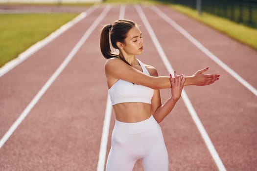 Standing and practicing. Young woman in sportive clothes is exercising outdoors.