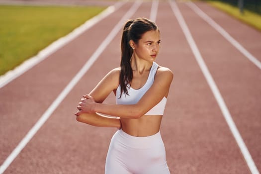 Standing and practicing. Young woman in sportive clothes is exercising outdoors.