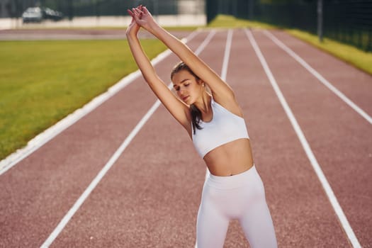 Standing and practicing. Young woman in sportive clothes is exercising outdoors.