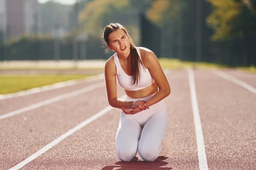 Front view. Young woman in sportive clothes is exercising outdoors.