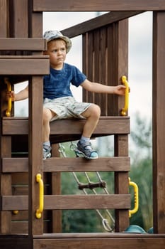 A cute little brave boy at the top of the playground. The child looks away in to distance