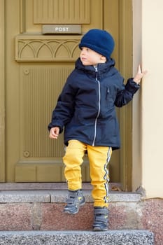 Cute boy on an autumn day at the door of the old post office.