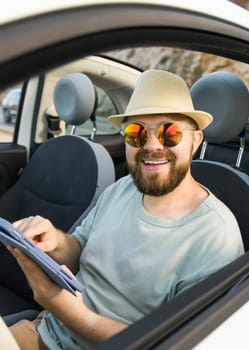 Bearded man using digital tablet inside car while travel and road trip vacation holidays - road map and navigation