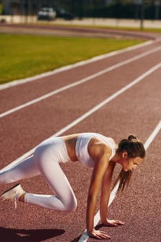 Stretching exercises. Young woman in sportive clothes is doing fitness outdoors.
