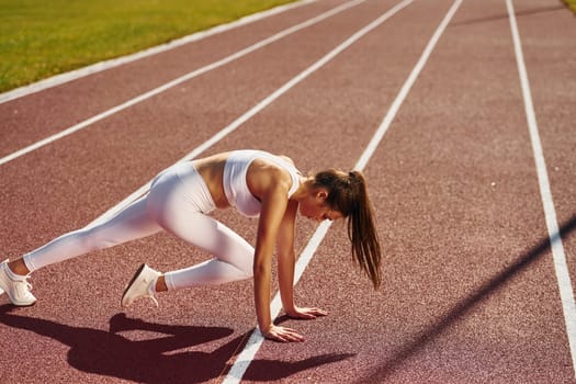 Stretching exercises. Young woman in sportive clothes is doing fitness outdoors.