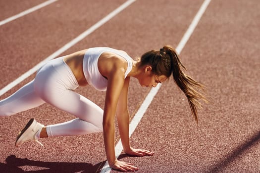 Stretching exercises. Young woman in sportive clothes is doing fitness outdoors.